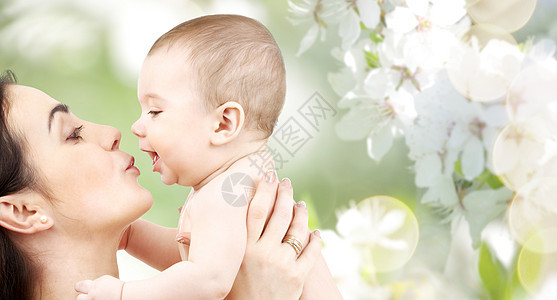 家庭,母亲,养育,人儿童保育的快乐的母亲亲吻可爱的婴儿绿色的自然背景图片