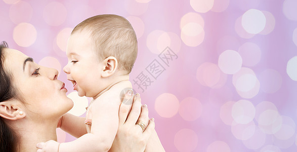 家庭,母亲,养育,人儿童护理的快乐的母亲亲吻可爱的婴儿紫色的灯光背景图片