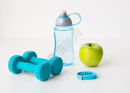 运动,健康的生活方式物品哑铃与健身跟踪器,绿色苹果水瓶白色背景图片