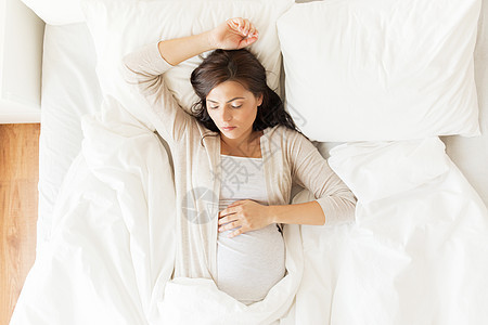 怀孕,休息,人期望的快乐的孕妇睡家里的床上图片