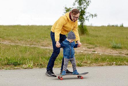 家庭,童,父亲,休闲人的快乐的父亲教小儿子骑滑板图片