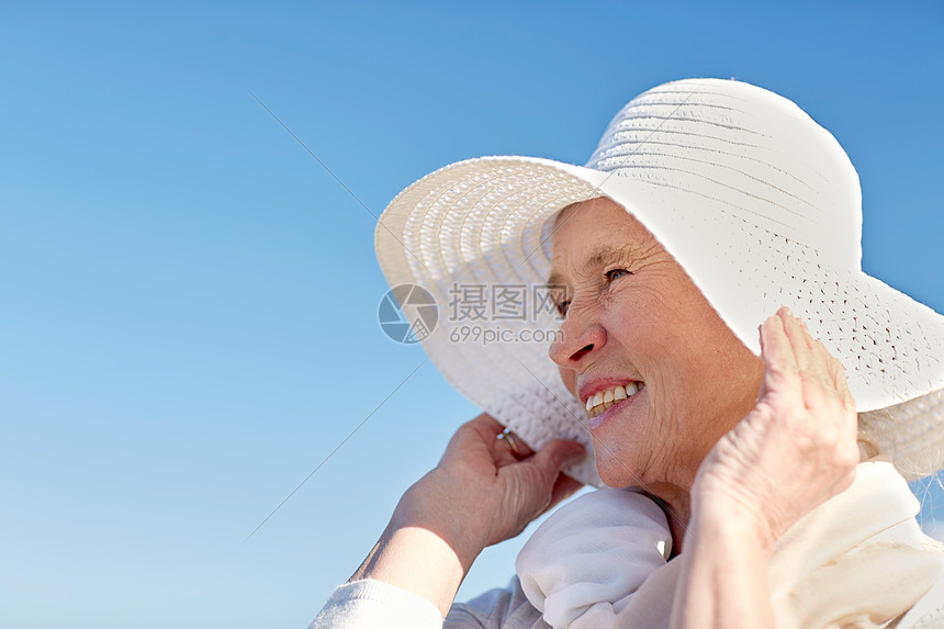 龄,休闲人的快乐的老妇女戴着太阳帽夏天的海滩上图片