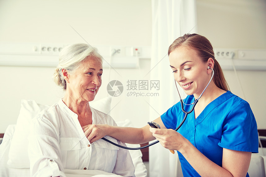 医学龄支持保健人的医生护士用听诊器访问老妇女并检查她的心跳医院