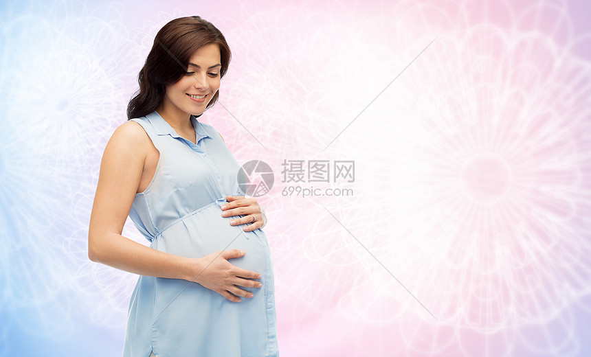 怀孕母亲人期望的快乐的孕妇触摸她的大肚子玫瑰石英宁静模式背景