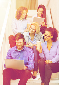 商业,技术创业微笑的创意队与笔记本电脑平板电脑坐楼梯上图片