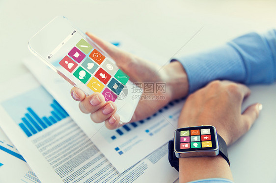 商业,技术人的近距离的女手着透明的智能手机智能手表屏幕上的办公室图片