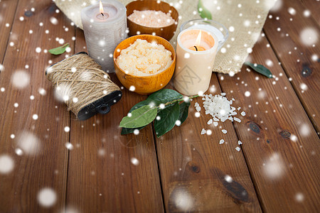 燃烧的蜡烛美容,水疗,治疗,天然化妆品健康身体擦洗与喜马拉雅粉红色盐蜡烛雪地上的木材背景