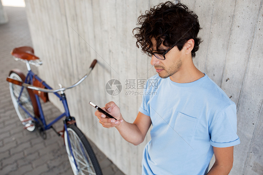 人们,通信,技术,休闲生活方式时髦的男人智能手机上发短信,城市街道上骑固定齿轮自行车图片