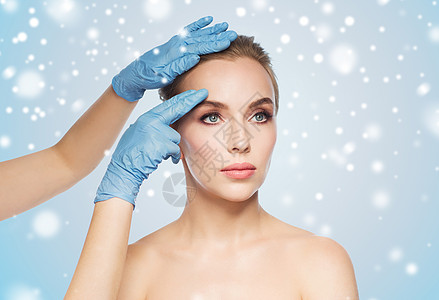 人,美容,整形手术美容外科医生美容师手触摸女人的脸蓝色的背景雪图片