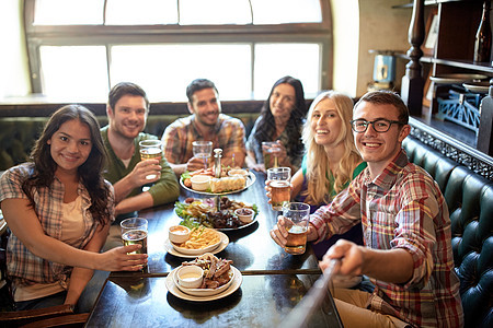 人休闲友谊技术快乐的朋友用自拍棒拍照,喝啤酒,酒吧酒吧吃零食图片