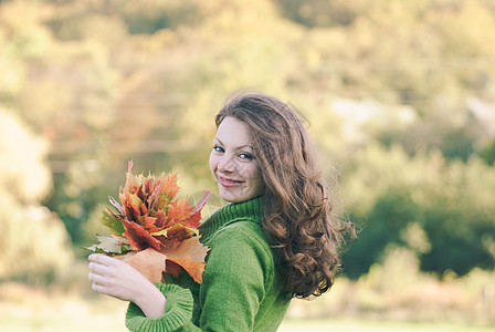 美丽的黑发女人带枫叶,秋天的背景与图片