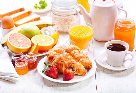 早餐桌上牛角包咖啡橙汁烤包水果背景图片