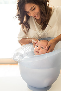 可爱的新生婴儿由母亲洗澡图片