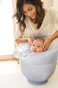 洗澡桶可爱的新生婴儿由母亲洗澡背景