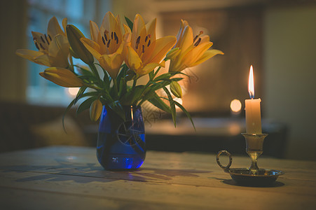 支点燃的蜡烛个花瓶,餐厅的桌子上放着盛开的百合花背景图片