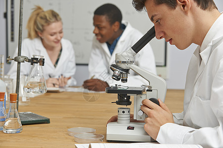 理科的十几岁学生用显微镜背景图片