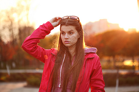 户外徒步位美丽的轻旅行者女士的肖像,带着背包,明亮的橙色晚霞,沿着欧洲旅行,自由积极的生活方式背景