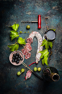 意大利美食生活方式与意大利腊肠,红酒,葡萄叶橄榄黑暗的背景,顶部的视野意大利食物的平躺图片