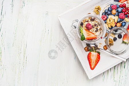 健康早餐准备米斯利罐子与夏季新鲜浆果,种子坚果轻木背景,顶部视图,文字的地方图片