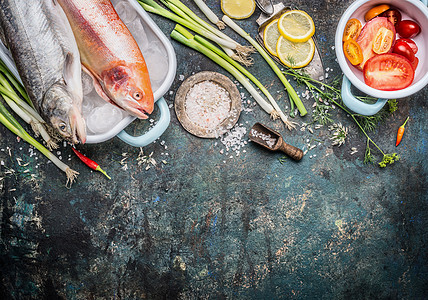 鱼盘烹饪准备与生全鳟鱼金虹鳟鱼配料黑暗的乡村背景,顶部的视图,边界健康饮食的食物图片