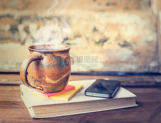复古杯与热饮料蒸汽,T恤咖啡旧书与智能手机黑暗的乡村木制桌子图片