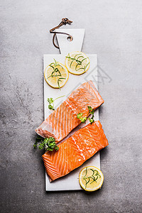 生鲑鱼鱼片与柠檬白色切割板,顶部视图图片