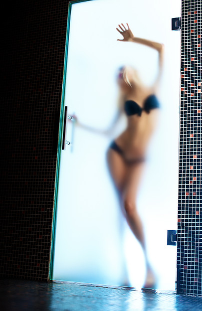 轻感苗条的女人穿着黑色内衣站现代浴室的璃门后图片