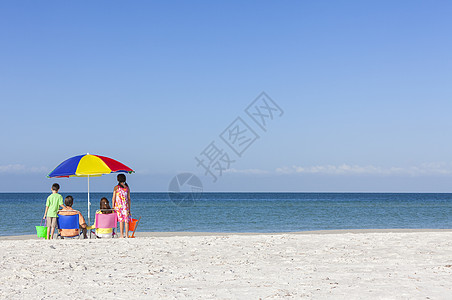 个幸福的家庭的母亲父亲,父母的女儿儿子的孩子坐躺椅下的伞个荒芜的阳光海滩图片