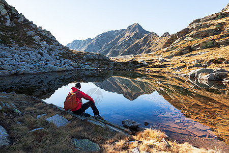 男徒步旅行者坐山湖旁边休息秋天阳光明媚的天意大利西部阿尔卑斯山,奥罗帕,皮埃蒙特,意大利,欧洲背景图片