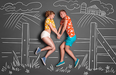 快乐情人节的爱情故事,害羞的浪漫夫妇坐树篱上,双手着粉笔画背景的农村夏天图片
