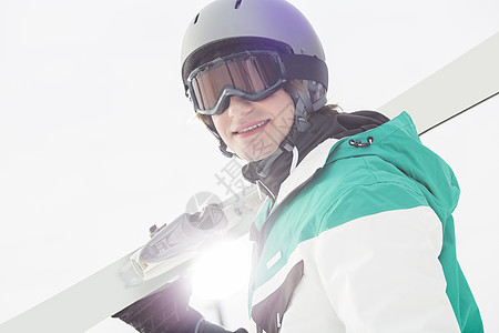 微笑的轻人晴朗的天空上扛着滑雪板的肖像图片