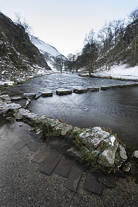流经雪的河流覆盖了山谷中的冬季景观图片