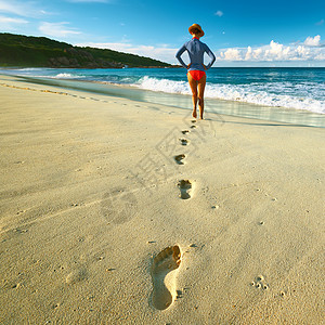 塞舌尔美丽海滩的女人沙滩上散步专注于脚印图片