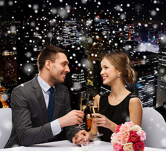 庆祝,诞节,假日人们的微笑的夫妇雪夜城市背景的餐厅碰杯泡葡萄酒图片