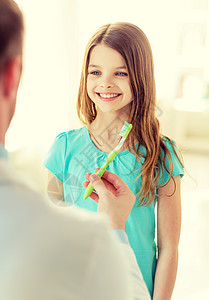 保健,儿童医学男医生给微笑的小女孩牙刷图片