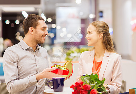 爱情,浪漫,情人节,夫妇人的幸福的轻夫妇与红花打开礼品盒咖啡馆购物中心图片
