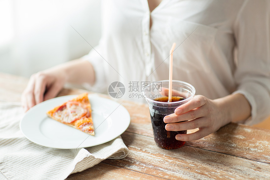 快餐,人健康的饮食观念靠近女人的手与比萨饼可口可乐饮料坐桌子上图片