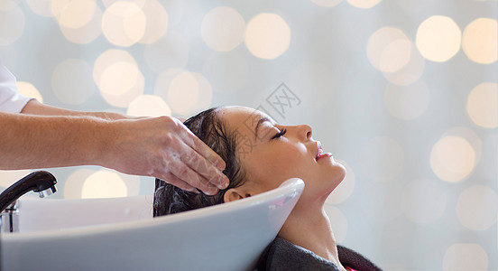 美容院,护发人的理发师洗手快乐的轻女人头上的假日灯光背景背景图片