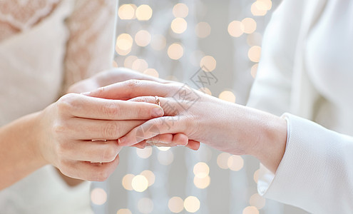 人,同婚姻爱情亲密的快乐女夫妇的手戴上结婚戒指节日的灯光背景图片