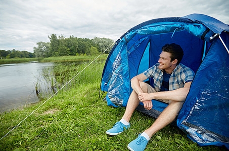 旅行,旅游,徒步旅行,设备人的快乐的轻人坐帐篷里露营湖边河岸生活方式高清图片素材