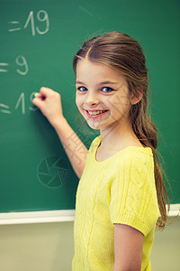 微笑的女学生教室的绿色粉笔板上写数字图片