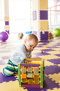 蹒跚学步的男孩游戏室里玩精细的运动技能立方体图片