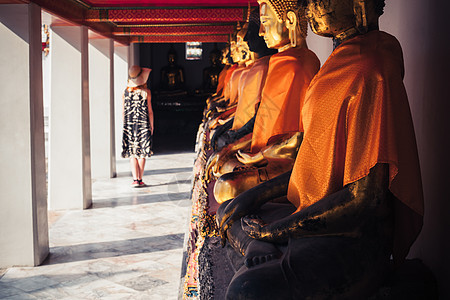 一个年轻的女人正看寺庙里的排佛像地方高清图片素材