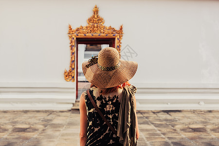 一个年轻的女人正看座佛教寺庙的精致入口图片