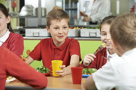 群学生坐学校自助餐厅的桌子上吃饭图片
