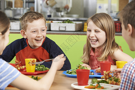 群学生坐学校自助餐厅的桌子上吃饭图片