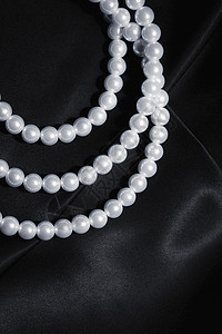 白色珍珠项链上的黑色丝绸特写图片