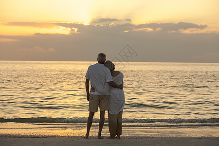 老男女夫妇日落日出时拥抱荒芜的热带海滩上高清图片