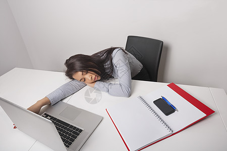 精疲力竭的女商人睡办公桌前图片