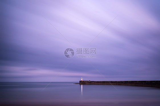 美丽的长曝光景观灯塔日落与平静的海洋图片
